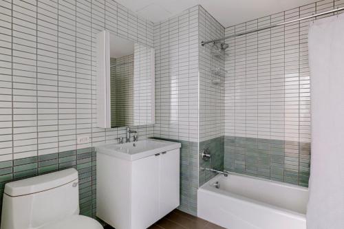 uma casa de banho com um WC, um lavatório e uma banheira em Blueground Hudson Yards sports fitness wd NYC-1484 em Nova York