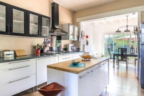 une grande cuisine avec des placards blancs et une table dans l'établissement Maison conviviale en lisière de forêt près du lac, à Biscarrosse