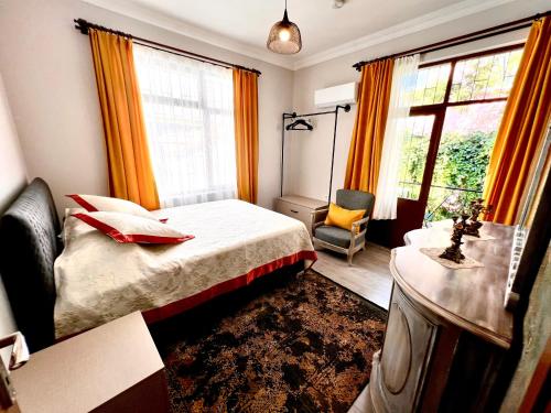 a bedroom with a bed and a chair and windows at Konukzade OldTown Apart in Antalya