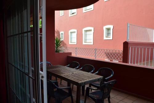 uma mesa e cadeiras numa varanda com uma parede vermelha em Islantilla Club by Linin em Lepe