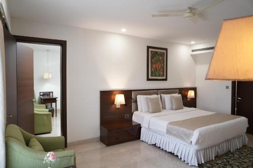 Habitación de hotel con cama y silla en The Alcor Hotel, en Jamshedpur