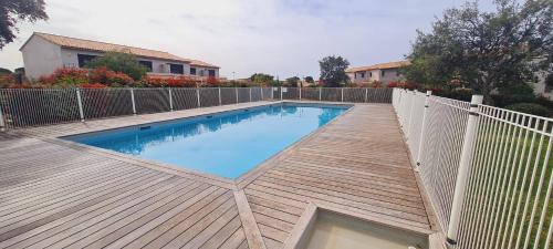 une piscine avec une terrasse en bois et une clôture dans l'établissement Mini villa Bay, 6 pers, piscine, 400 m plage, à Lecci