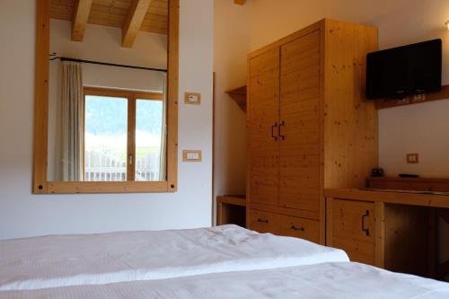 a bedroom with a bed and a television and a window at B&B Longanorbait in Folgaria