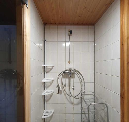 a shower in a white tiled bathroom with shelves at Kelotupa 19 in Syöte