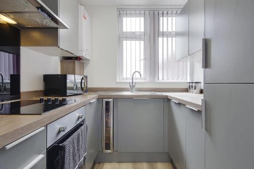 a kitchen with white cabinets and a sink at Wimbourne Road Apartment 2 in Bournemouth