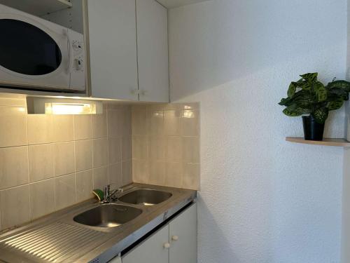 una pequeña cocina con fregadero y microondas en Appartement Fleury-Saint-Pierre-la-Mer, 1 pièce, 2 personnes - FR-1-229D-232, en Saint Pierre La Mer