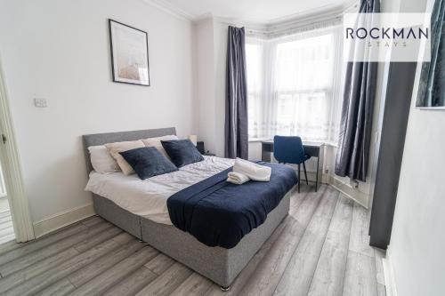 ein Schlafzimmer mit einem Bett mit blauen Kissen in der Unterkunft Grove House 8 Bed Apartment Close To Beach with Parking by RockmanStays in Southend-on-Sea