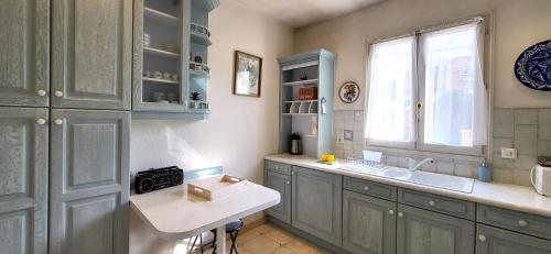 una cucina con armadi blu, lavandino e finestra di Color - Charmant appartement proche RER B & C avec Jardin a Verrières-le-Buisson