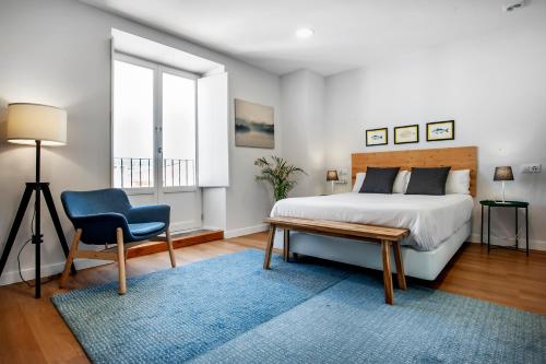 a bedroom with a bed and a chair and a window at HOTEL CAMINO do EUME in Puentedeume