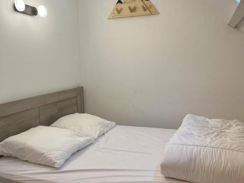 un lit blanc avec deux oreillers dessus dans l'établissement Appartement T4 rénové, proche centre, 3 chambres, 6/8 pers, équipé, est/ouest, dispo de suite - FR-1-234-254, à Cauterets