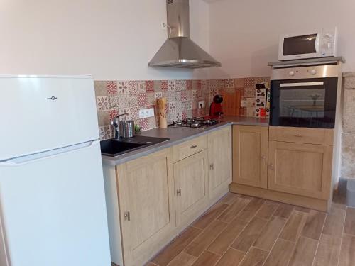 a kitchen with wooden cabinets and a sink and a refrigerator at Maison a la Laiterie in La Gaubretière