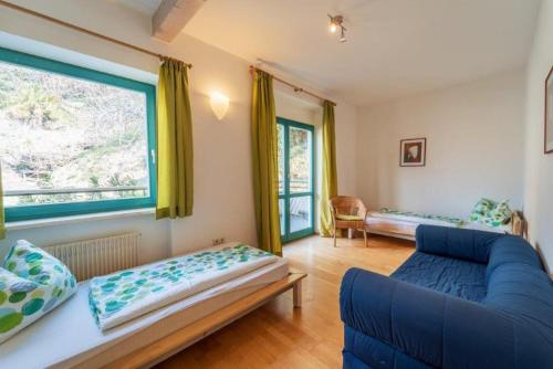 Una sala de estar con un sofá azul y una ventana. en Passerhaus Schenna, en Scena