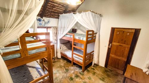 a room with two bunk beds and a door at Kitesurf Tofo House in Praia do Tofo