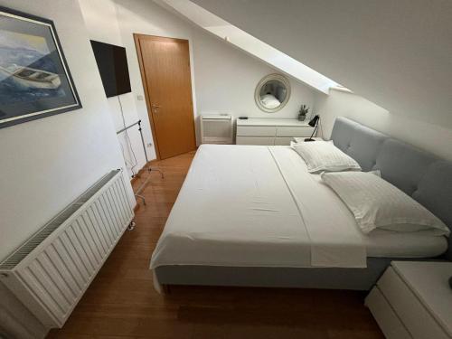 a large white bed in a small room at Penthouse Villa Spomenka top floor apartment on central beach in Podgora