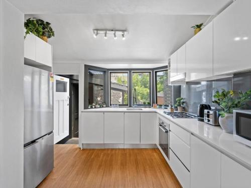 a large white kitchen with white cabinets and wood floors at Quaint Aussie 2Br plus 1 loft - Casino & ICC & Chinatown & Darling Harbour & Fish Market in Sydney
