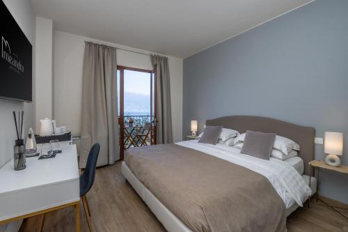 a bedroom with a bed and a desk and a window at Hotel Meandro - Lake View in Gargnano