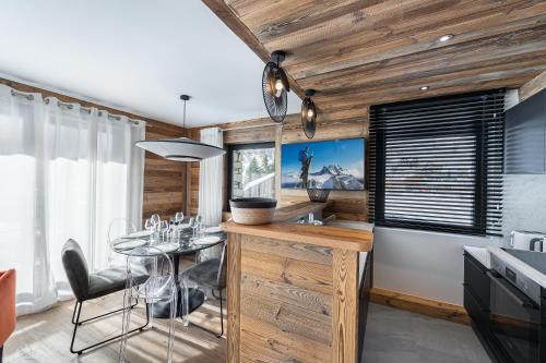 - une cuisine avec des murs en bois, une table et des chaises dans l'établissement Appartement Blanchot - LES CHALETS COVAREL, à Val dʼIsère