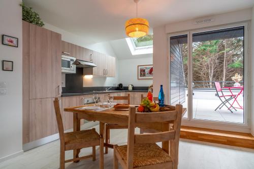 une cuisine avec une table et des chaises en bois ainsi qu'une fenêtre dans l'établissement Ty Kenlou du Cabellou - Appartement sur la plage, à Concarneau