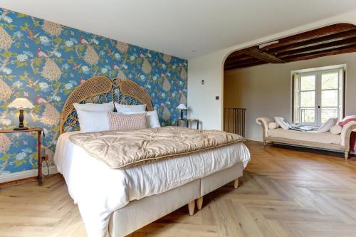 a bedroom with a large bed and a chair at La petite châtelaine - Charmante maison au calme in Saponay