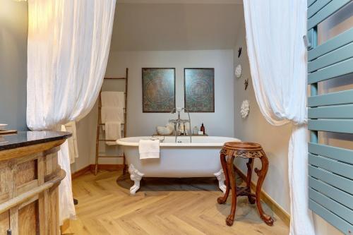 ein Badezimmer mit einer weißen Badewanne und einem Waschbecken in der Unterkunft La petite châtelaine - Charmante maison au calme 