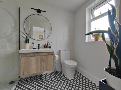 Modern large en suite loft room in Bromley, London في Bickley: حمام مع حوض ومرحاض ومرآة
