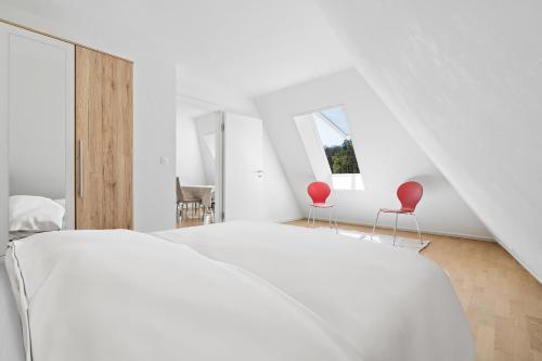 een slaapkamer met een wit bed en 2 rode stoelen bij Boissonnet 96 Residence by Homenhancement in Lausanne