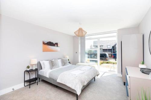 biała sypialnia z łóżkiem i dużym oknem w obiekcie Close to beach, parking, 2 bed flat with garden - Meraki Luxe w mieście Southbourne