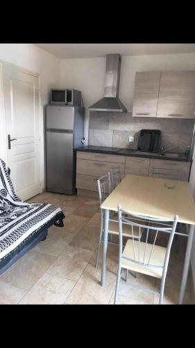une cuisine avec une table, des chaises et un réfrigérateur dans l'établissement Appartement proche des plages, à Porto-Vecchio