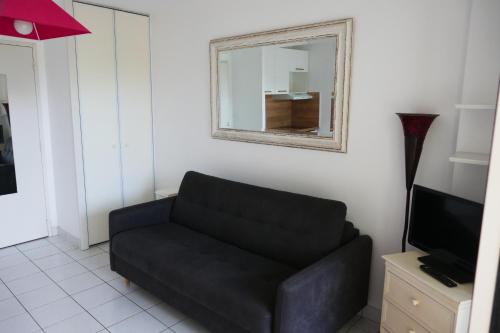 - un canapé noir dans le salon avec un miroir dans l'établissement ROYAL PARK La BAULE PISCINES, à La Baule