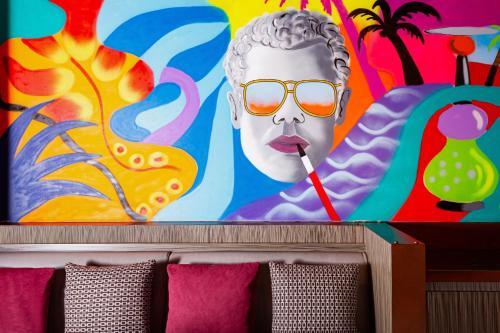 a wall with a painting of a statue with a straw at Baku Marriott Hotel Boulevard in Baku