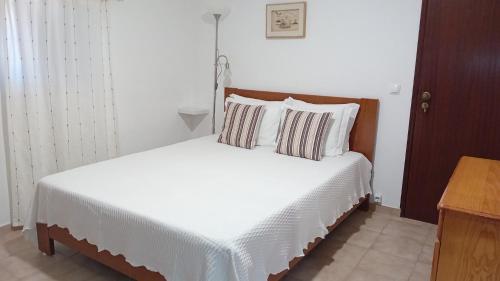 a bedroom with a bed with white sheets and pillows at Apartamentos na Quinta Altavista do Carvalhal in Zambujeira do Mar
