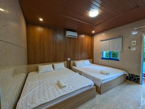 - 2 lits dans une chambre dotée de murs en bois dans l'établissement Biển Xanh Homestay, à Ly Son