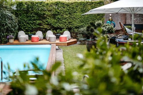 a pool with a table and chairs and an umbrella at Das Esel - Kleinod in Rust in Rust