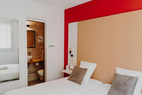 sypialnia z białym łóżkiem i czerwoną ścianą w obiekcie L'Hôtel Bristol w Caen