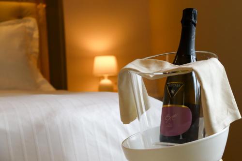 a bottle of wine in a bucket on a bed at Villa Nonna Cicci Boutique Hotel - SPA in Cisterna dʼAsti