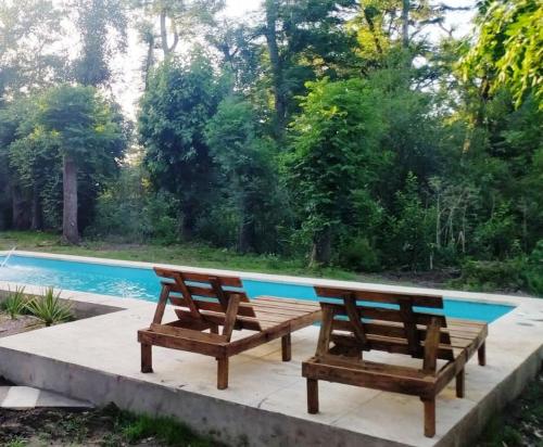 dois bancos de madeira sentados ao lado de uma piscina em Quinta Los Altares em Bragado