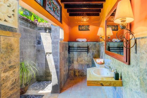 an orange bathroom with a sink and a mirror at Jineng 5 BR Private Pool Villa with Stunning Garden by Basma Groups in Ubud