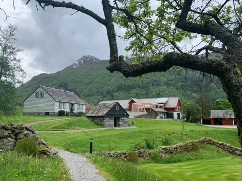 uma estrada que leva a uma fazenda com casas e uma montanha em Guddals Tunet em Rosendal