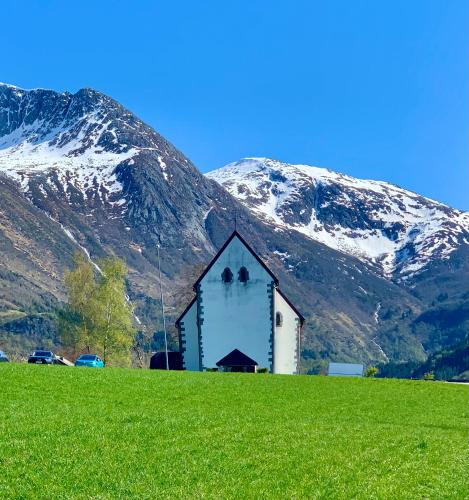 a church in a field with mountains in the background at Guddals Tunet in Rosendal