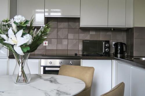 a vase of flowers on a table in a kitchen at Stunning Waterfront View Apartment by BOLD Apartments in Liverpool