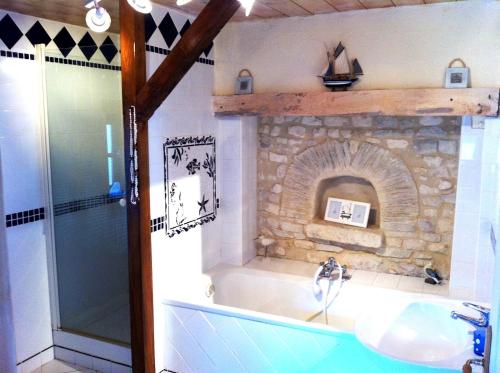 a bathroom with a sink and a stone fireplace at Maison spacieuse avec piscine et vue sur jardin à Fourches in Fourches