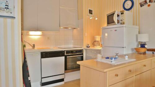 uma cozinha com electrodomésticos brancos e um frigorífico branco em T2 au 1er étage - SAINT CAST LE GUILDO em La Garde