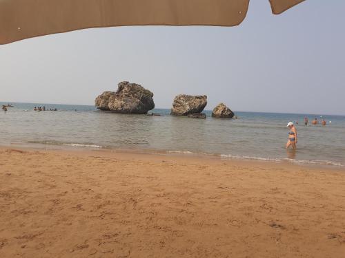 a person standing on a beach with rocks in the water at BallaLo'... in Licata