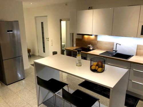 a kitchen with a counter with chairs and a refrigerator at Traumhaftes Loft Wintergarten in Schwabach