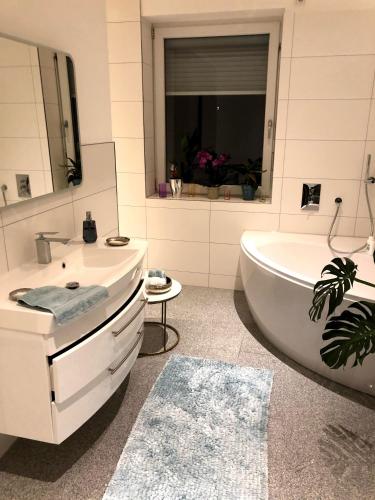 a white bathroom with a tub and a sink at Traumhaftes Loft Wintergarten in Schwabach