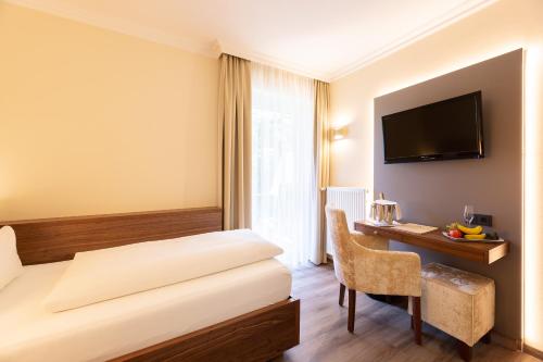 a hotel room with a bed and a desk and a television at Holzapfel in Bad Füssing
