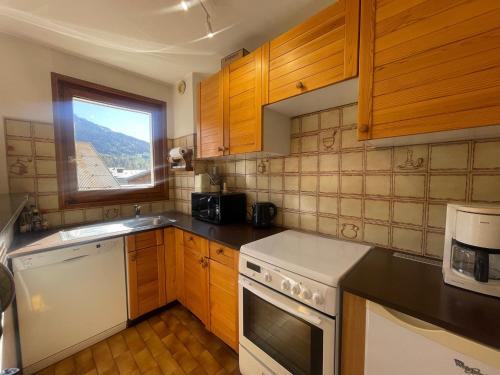 une cuisine avec des armoires en bois et un four blanc dans l'établissement Appartement T2 duplex au coeur de Samoëns, balcon, WIFI, animaux admis - FR-1-624-1, à Samoëns