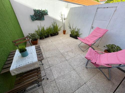 a patio with two chairs and a bench and plants at 100 Contos in Porto