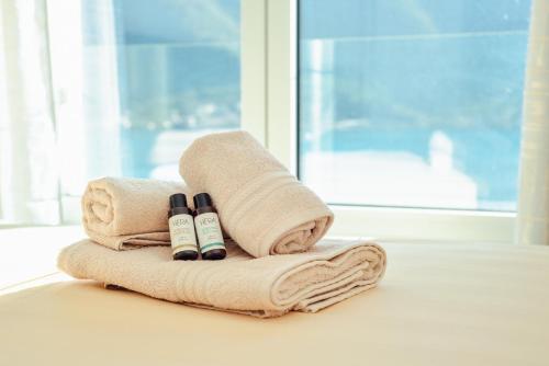 Dos toallas y dos botellas en una mesa junto a una ventana. en Sea view apartment for 4, en Kotor