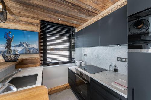 une cuisine avec des armoires noires et une fenêtre avec vue dans l'établissement Appartement Blanchot - LES CHALETS COVAREL, à Val dʼIsère